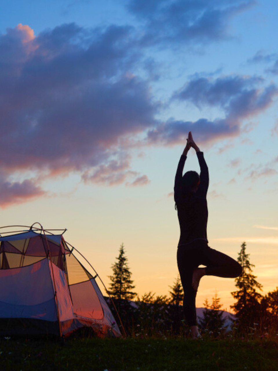 woman doing yoga at sunset next to a tent